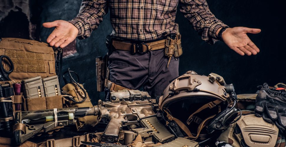Man in a checkered shirt showing his military uniform and equipment